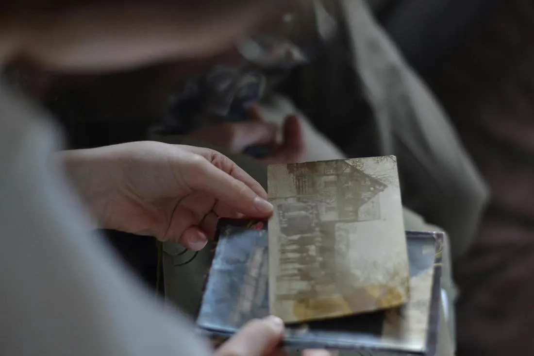 Mãos segurando uma fotografia antiga de uma casa
